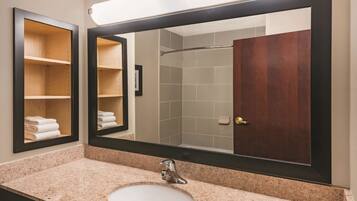 Un baño con un espejo grande, un lavabo y una ducha.