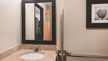 A bathroom with a granite countertop sink, a mirror, and a framed picture on the wall.