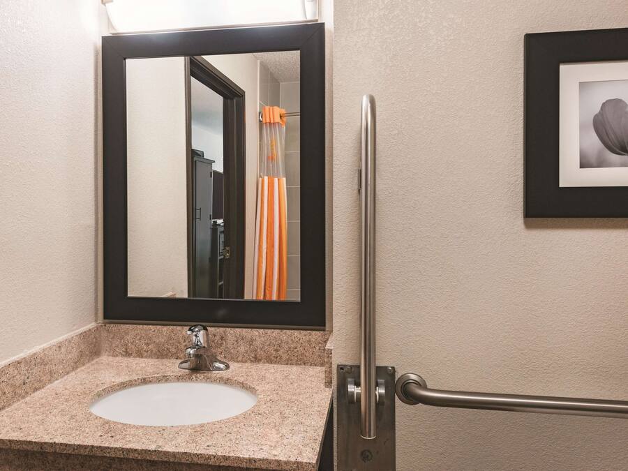 A bathroom with a granite countertop sink, a mirror, and a framed picture on the wall.