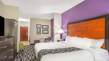 A hotel room with a large bed, a TV, a dresser, and a desk with a chair.