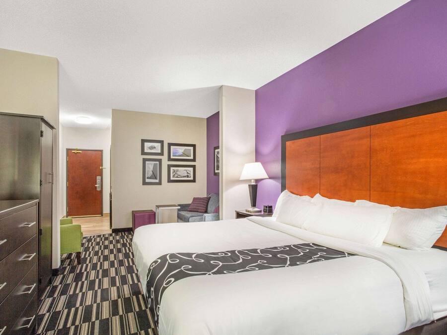 A hotel room with a large bed, a TV, a dresser, and a desk with a chair.