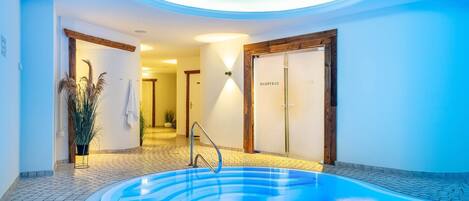 Un espacio de spa con un jacuzzi, puertas de madera y suelo de baldosas.