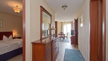 A hotel room with a bed, dresser, mirror, and a view of the hallway.