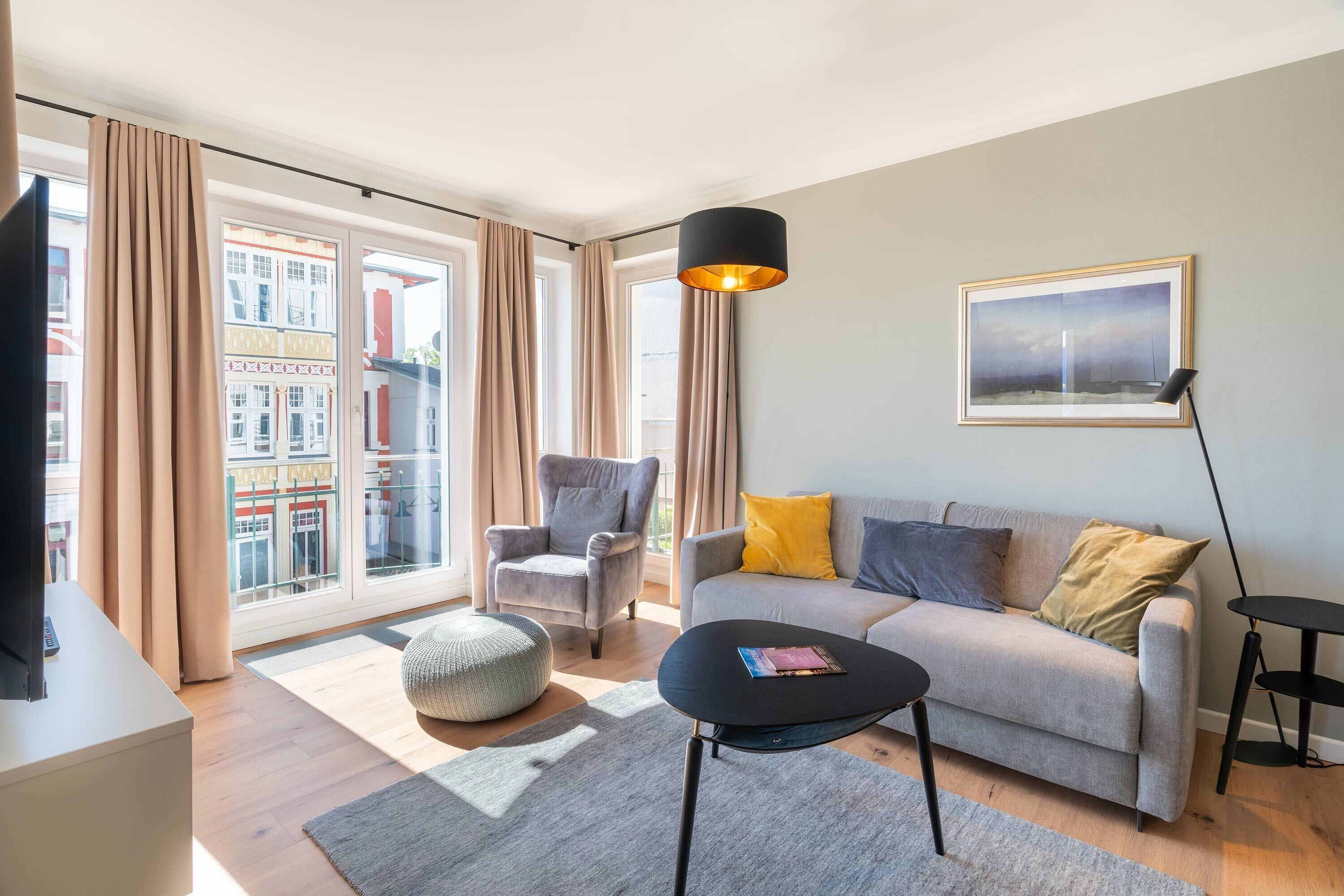 Una sala de estar moderna con sofá, sillón, reposapiés y una mesa de centro.