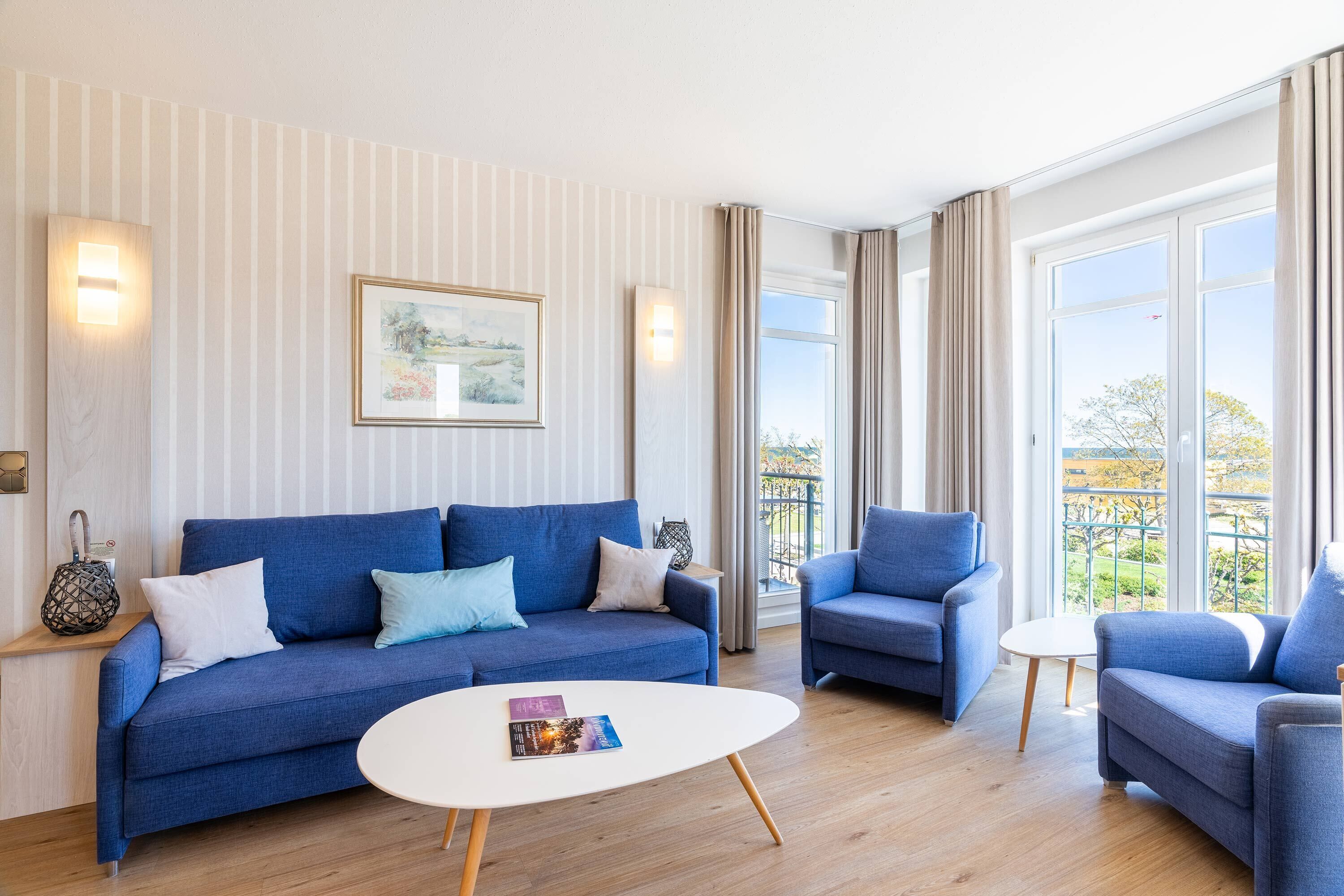 A modern living room with a blue sofa, a white coffee table, and a framed picture on the wall.
