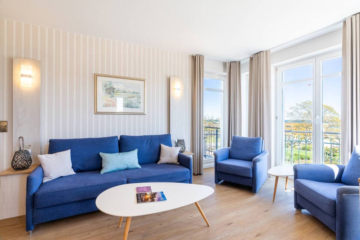 A modern living room with a blue sofa, a white coffee table, and a framed picture on the wall.