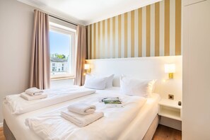 A hotel room with two beds, a window with curtains, a striped wall, and bedside lamps. - SEETELHOTEL Ostseeresidenz Ahlbeck (Heringsdorf)
