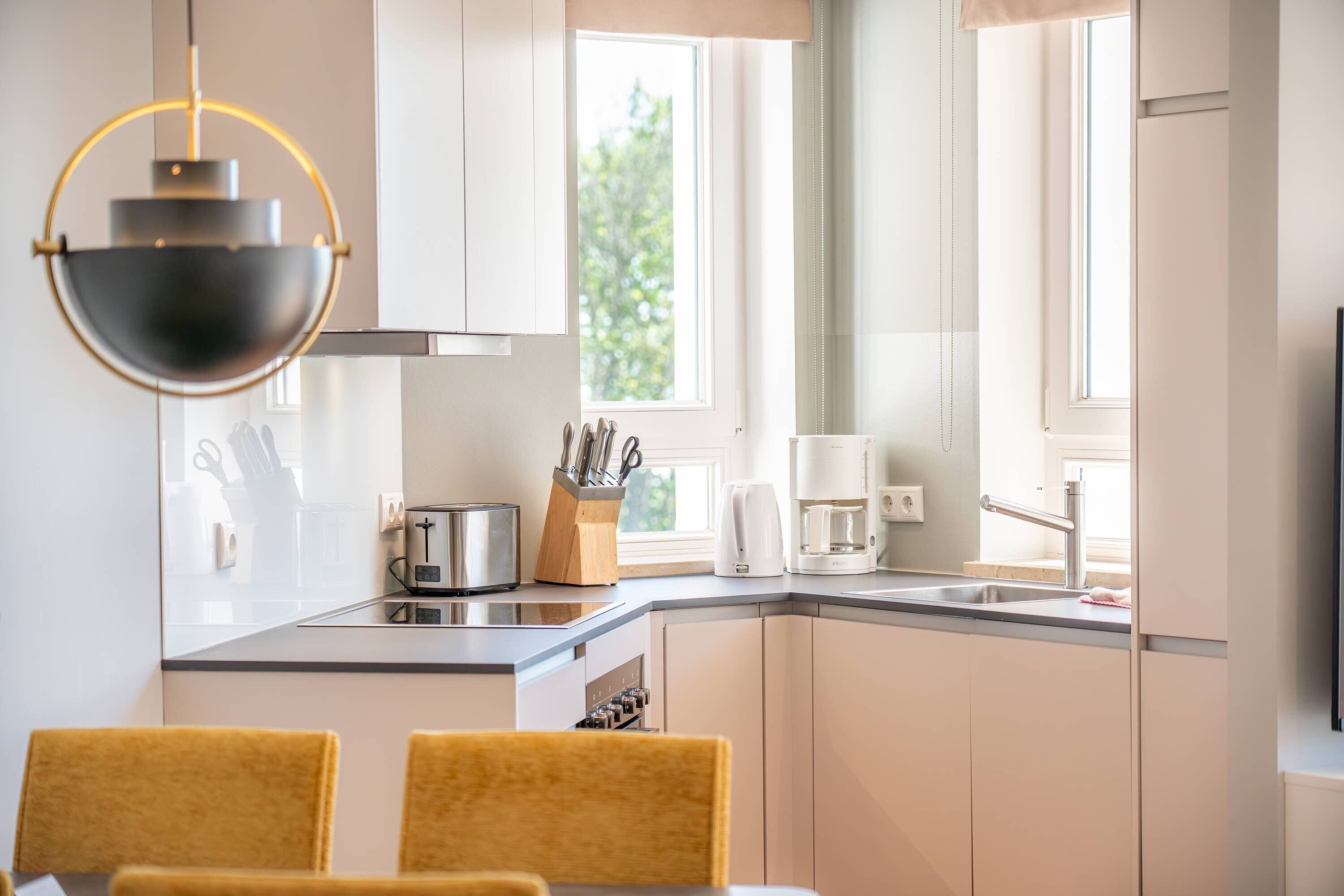 Una cocina moderna con comedor, con un amplio ventanal, electrodomésticos de acero inoxidable y una lámpara colgante.
