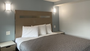 A neatly made bed with a wooden headboard, two bedside tables, and wall-mounted lights.