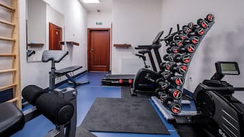 A gym with exercise equipment, a treadmill, and a wall-mounted dumbbell rack.
