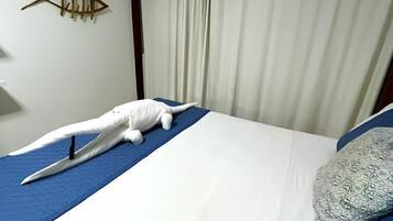 Quarto de hotel com uma cama, um peixe decorativo na parede e uma cortina.