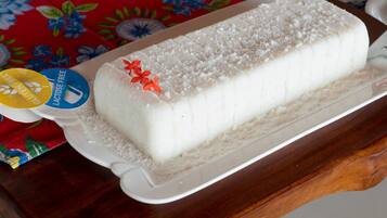 A loaf of gluten-free and lactose-free bread on a white plate with a floral tablecloth in the background.