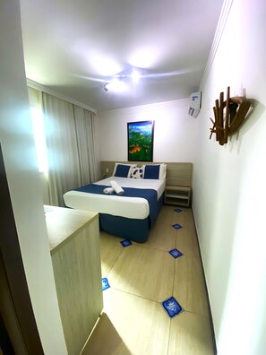 A hotel room with a bed, a painting on the wall, and a ceiling fan. - Pousada Bahia Inn (Cairu)