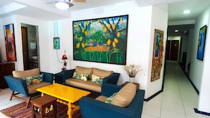 A living room with a sofa set, a coffee table, and a painting of a tree. - Pousada Bahia Inn (Cairu)