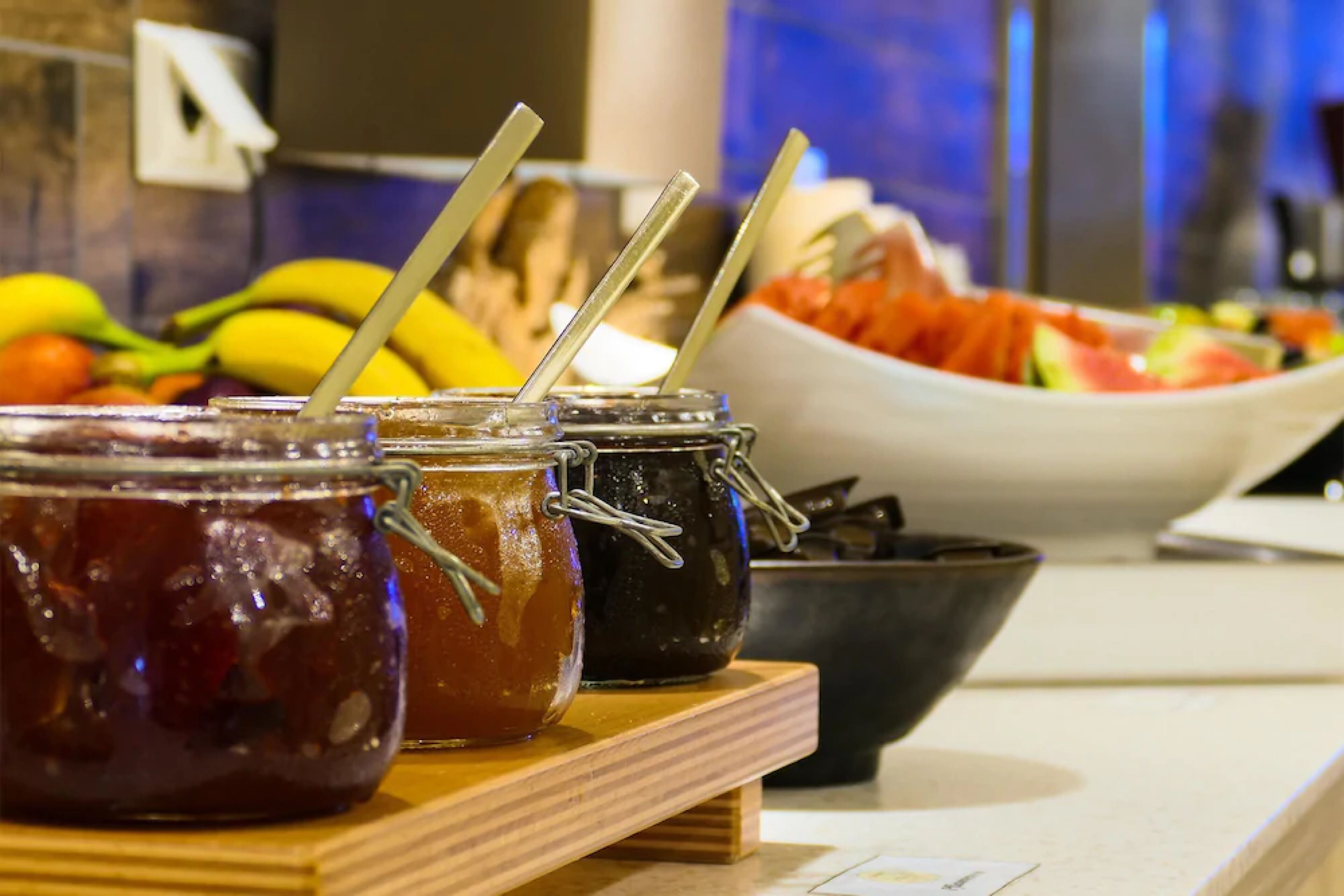 Un comptoir avec des pots de confitures et un saladier rempli de fruits.