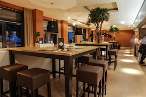 Uma área de refeições moderna com uma ilha central, banquetas de bar e um balcão comprido.