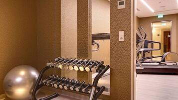 A gym area with a wall-mounted dumbbell rack, a large exercise ball, and a treadmill.