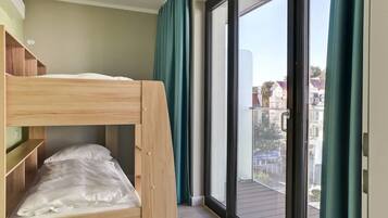 Una cama litera en una habitación con un gran ventanal corredera que da a un balcón exterior.