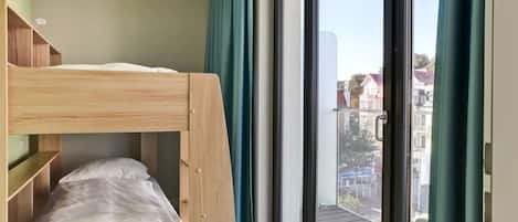 A bunk bed in a room with a large sliding glass door leading to an outdoor balcony.