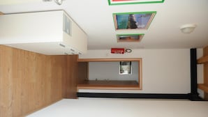 A room with a wooden floor, a white ceiling, and a small window. - Affittacamere Dormire Caldi (Borgo Valbelluna)