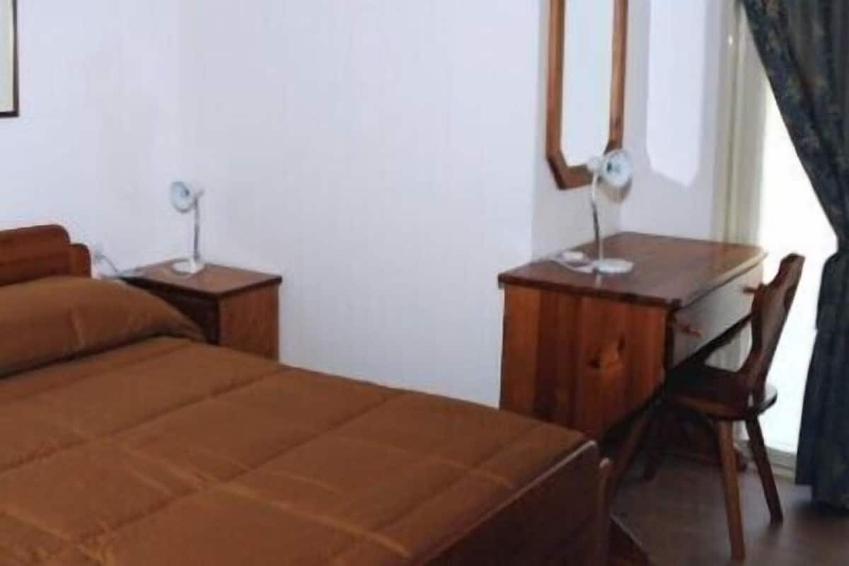 Um quarto com uma cama, uma escrivaninha e uma cadeira.