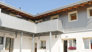 A modern building with a flat roof, multiple balconies, and windows. - Affittacamere Dormire Caldi (Borgo Valbelluna)