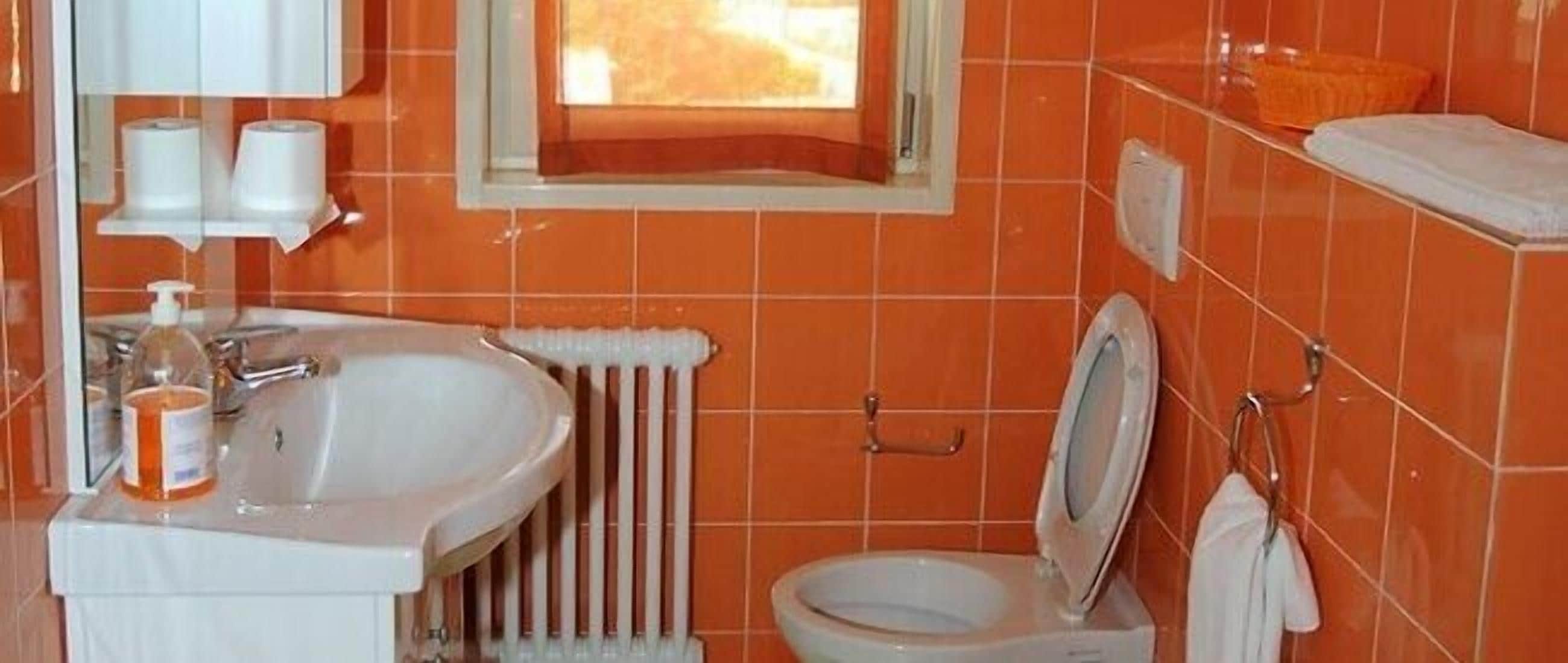 A bathroom with a sink, toilet, and a window.