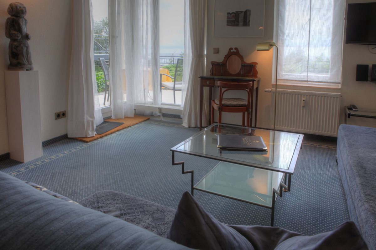 Una sala de estar moderna con una mesa de centro de vidrio, un sofá y vistas al exterior a través de grandes ventanales.