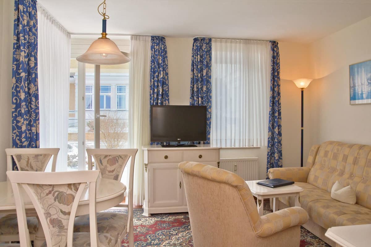 A living room with a television, a sofa, a table, and two chairs.