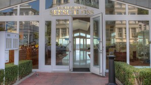 A hotel entrance with a glass facade, a sign reading "Ostseesiedlung Seeschloss," and a view of the interior through the glass.