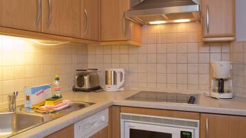 A kitchen with wooden cabinets, a stainless steel toaster, a coffee maker, and a microwave.