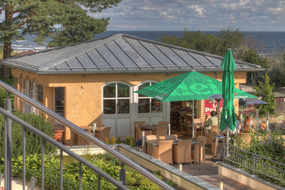 A coastal building with outdoor seating and a view of the sea.