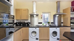 A modern kitchen with stainless steel appliances, wooden cabinets, and a central island. - Emporium City Centre Self Catering (Nottingham)