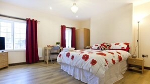 A bedroom with a large bed, a desk, a wardrobe, and a television. - Emporium City Centre Self Catering (Nottingham)