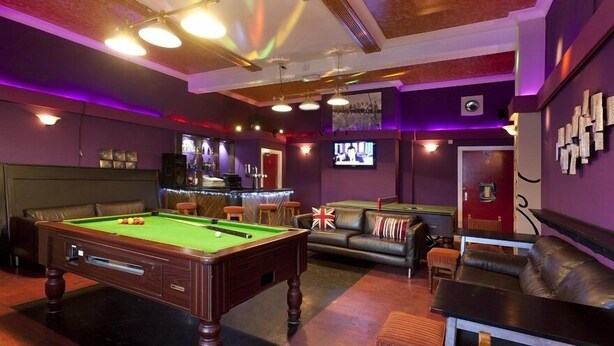 A billiards room with a pool table, leather sofas, and a bar area. - Emporium City Centre Self Catering (Nottingham)