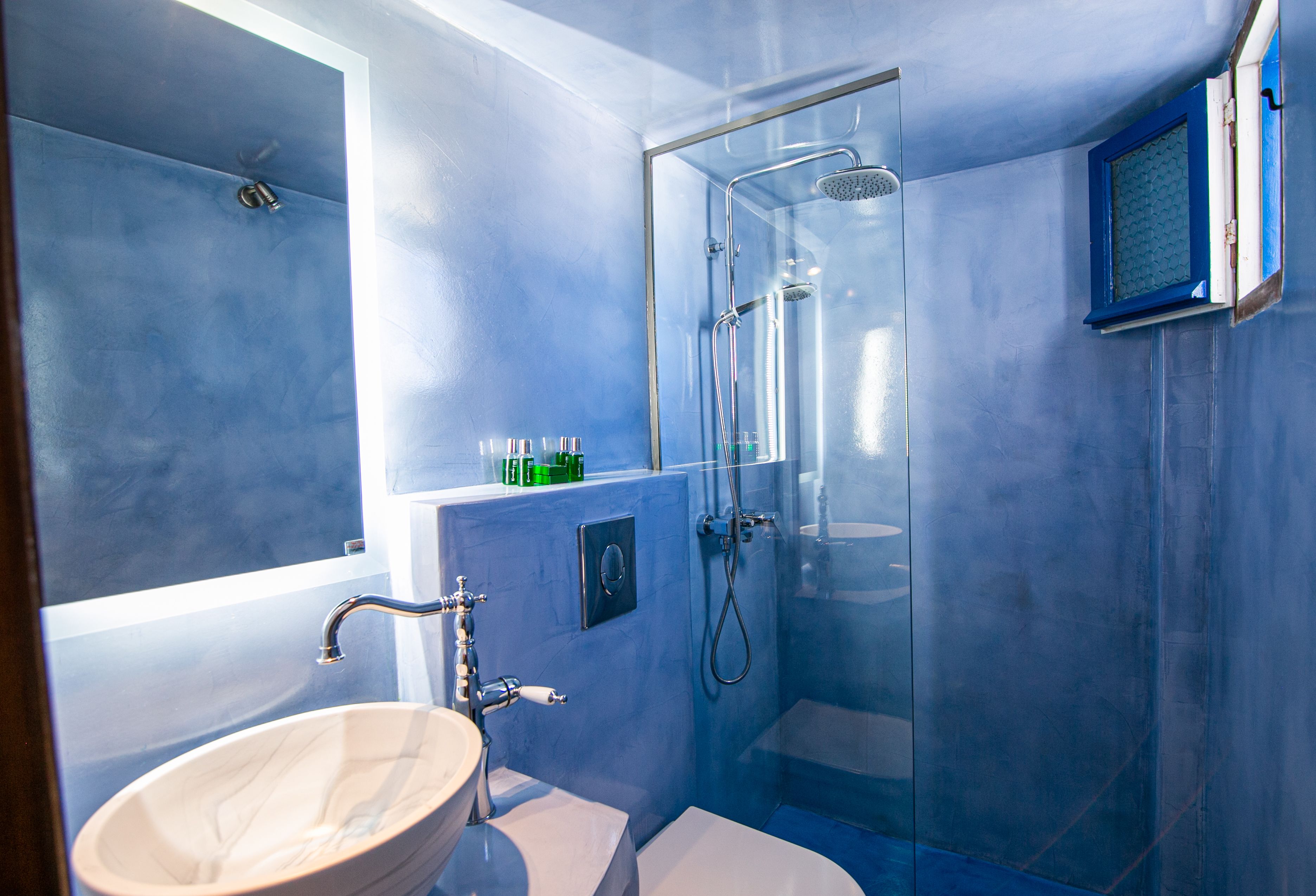 Een badkamer met een douchecabine van glas, een witte wastafel en een toilet.