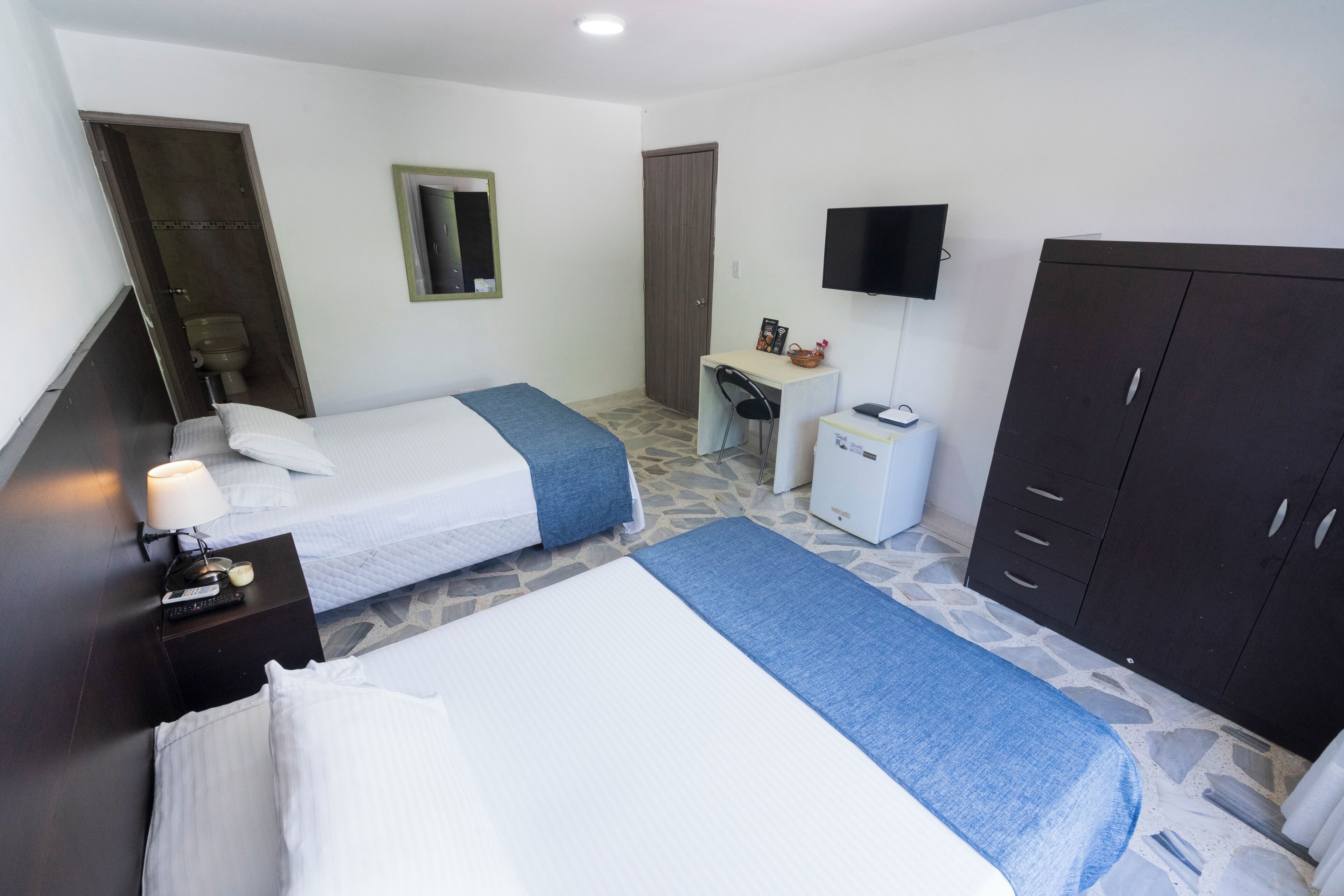 A hotel room with two beds, a desk, a television, and a wardrobe.