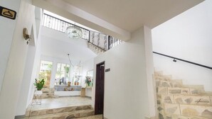 Ein geräumiger Innenraum mit einer Steintreppe, einem Chandelier und Blick ins Freie.