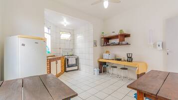 Une cuisine avec des carreaux blancs, un réfrigérateur, une cuisinière, un évier et une table en bois.