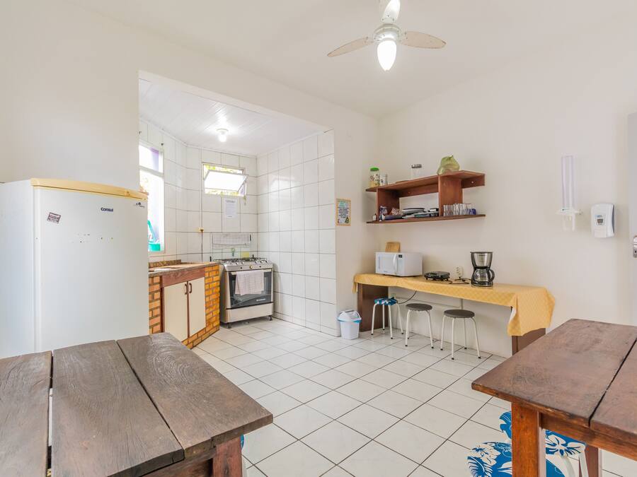 Une cuisine avec des carreaux blancs, un réfrigérateur, une cuisinière, un évier et une table en bois.
