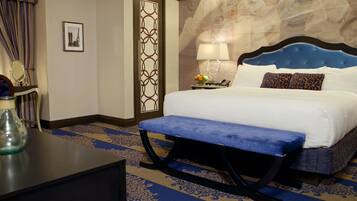 Une chambre d’hôtel comprenant un lit, une banquette, une table de chevet, une lampe, un miroir et un panneau décoratif mural.