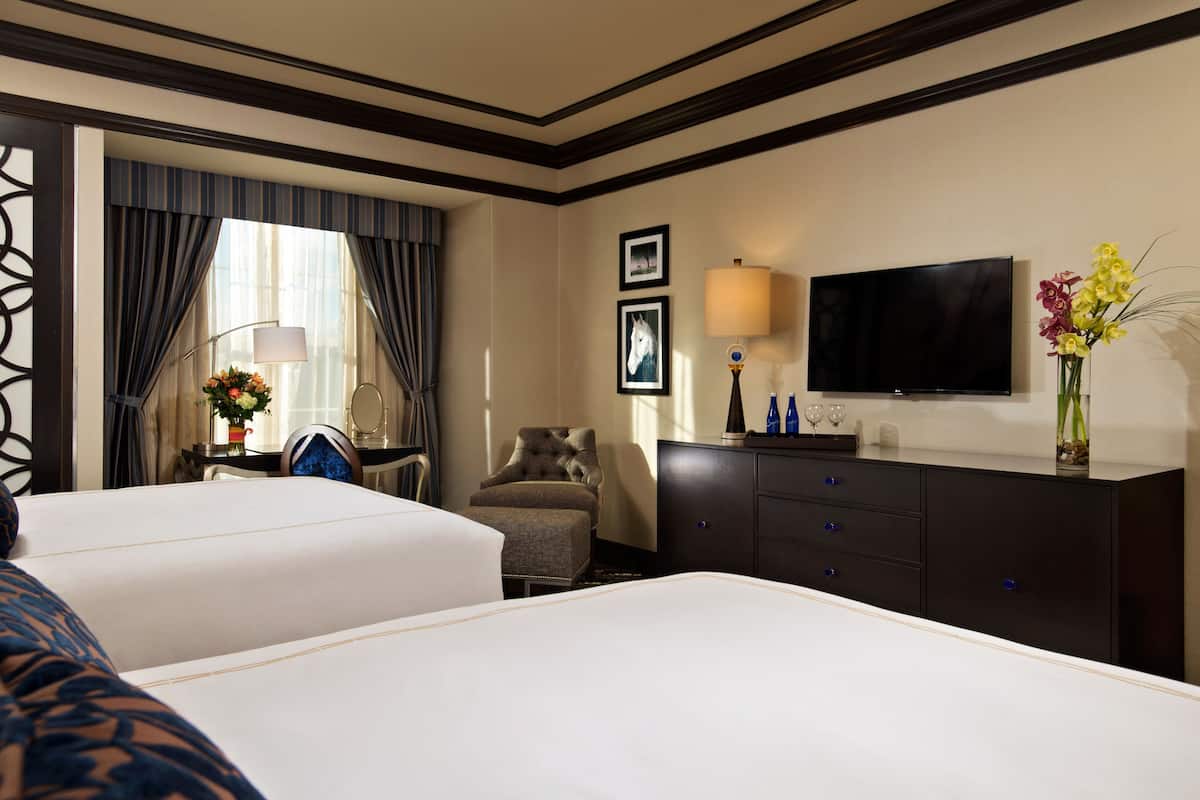 Une chambre d’hôtel avec deux lits, une télévision, un bureau avec une lampe et une chaise.