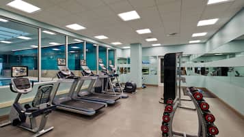Un gimnasio moderno con cintas de correr, elípticas y una zona de pesas.