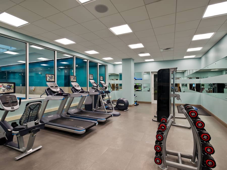 Un gimnasio moderno con cintas de correr, elípticas y una zona de pesas.