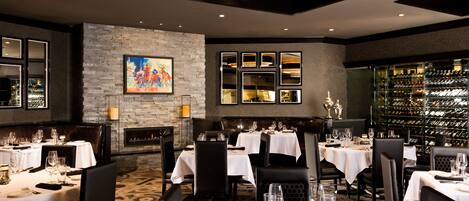 Un restaurant doté de nombreuses tables, d’une cheminée et d’une cave à vin.