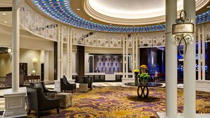 A grand lobby with a patterned carpet, seating area, and decorative columns. - Saratoga Casino Hotel (Saratoga Springs)