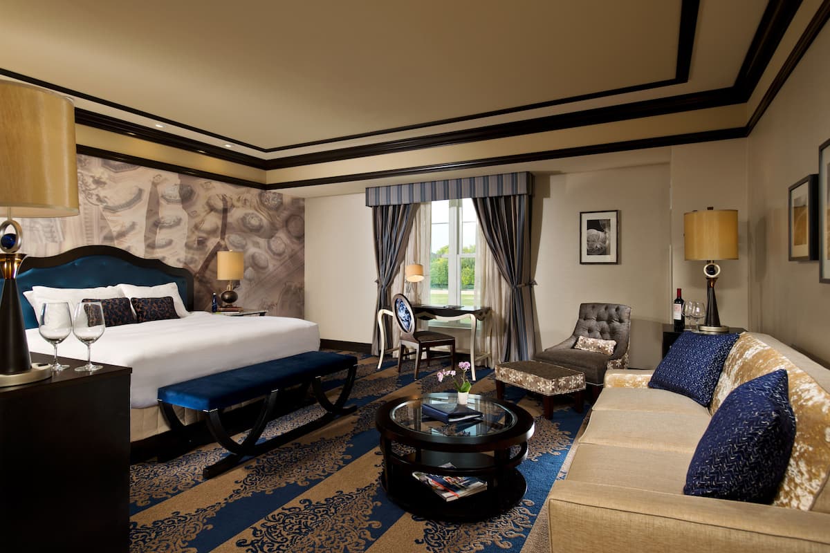 Une chambre d’hôtel avec un grand lit, un canapé, une table basse et un bureau avec une chaise.