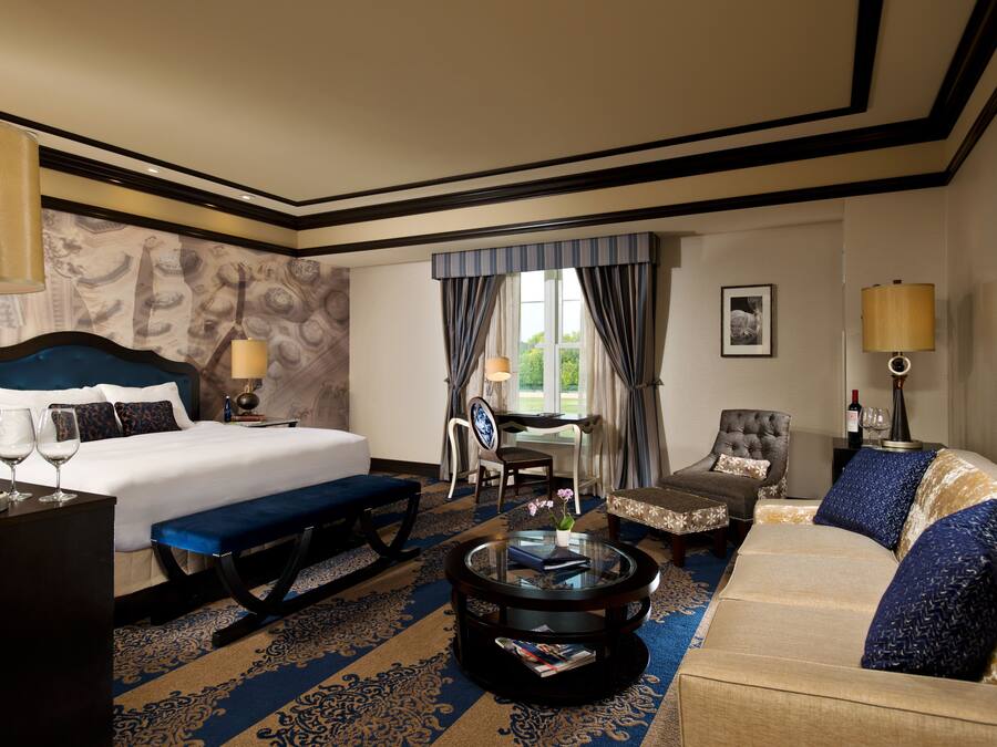 Une chambre d’hôtel avec un grand lit, un canapé, une table basse et un bureau avec une chaise.
