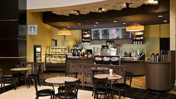 Interior de una cafetería Starbucks con mesas, mostrador y paneles con la carta.