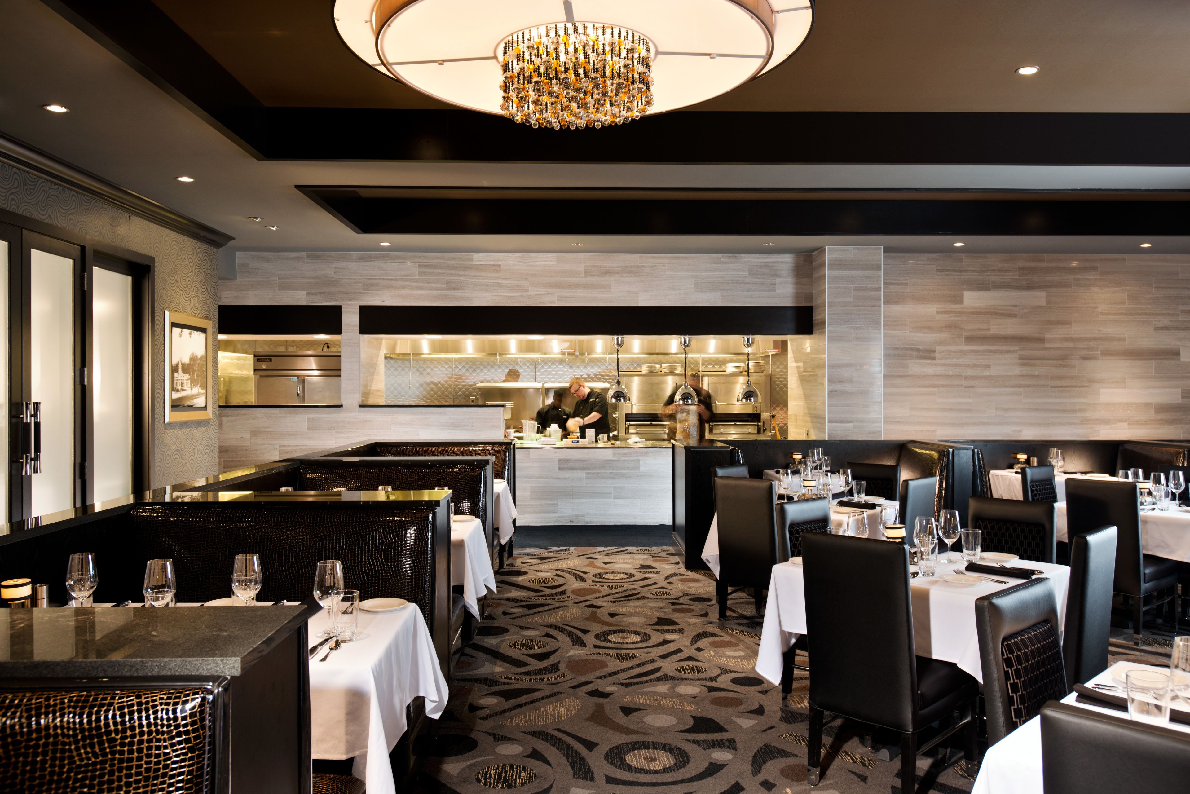 A restaurant with a central bar area, multiple dining tables with chairs, and a patterned carpet.